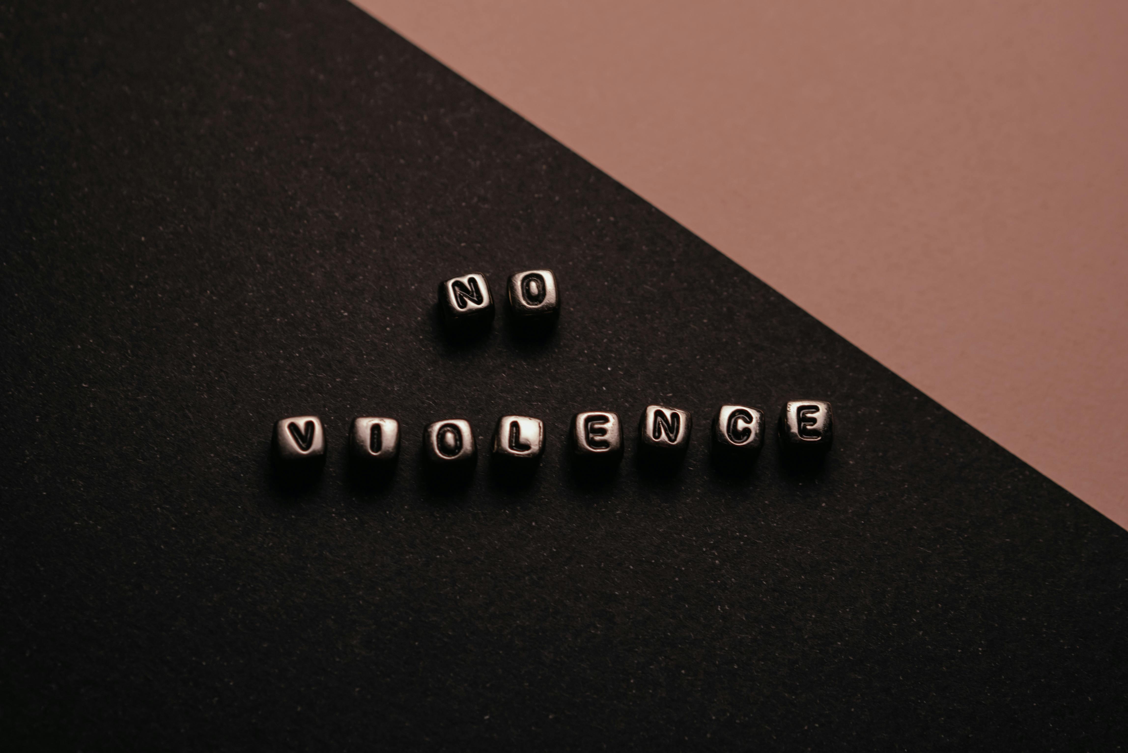 Beads that spell "No Violence" on a black and rose colored background