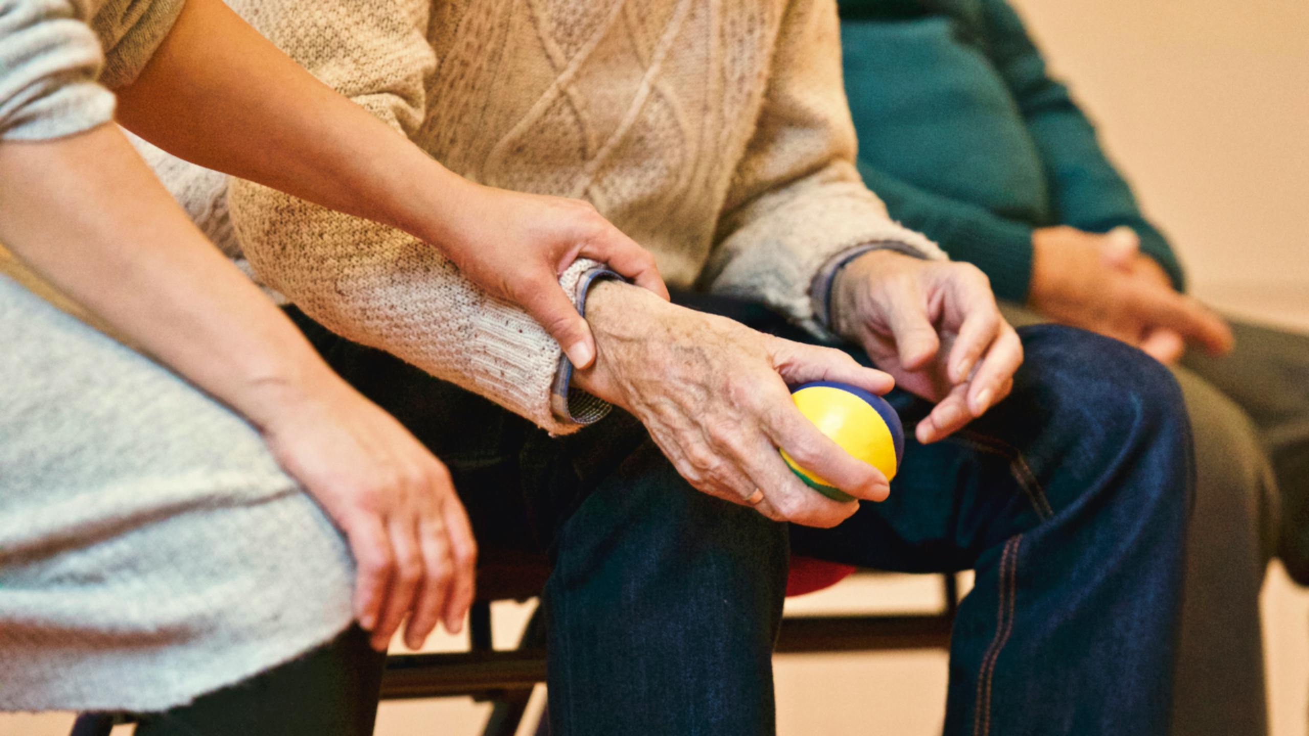 A caregiver holds the wrist of an older person