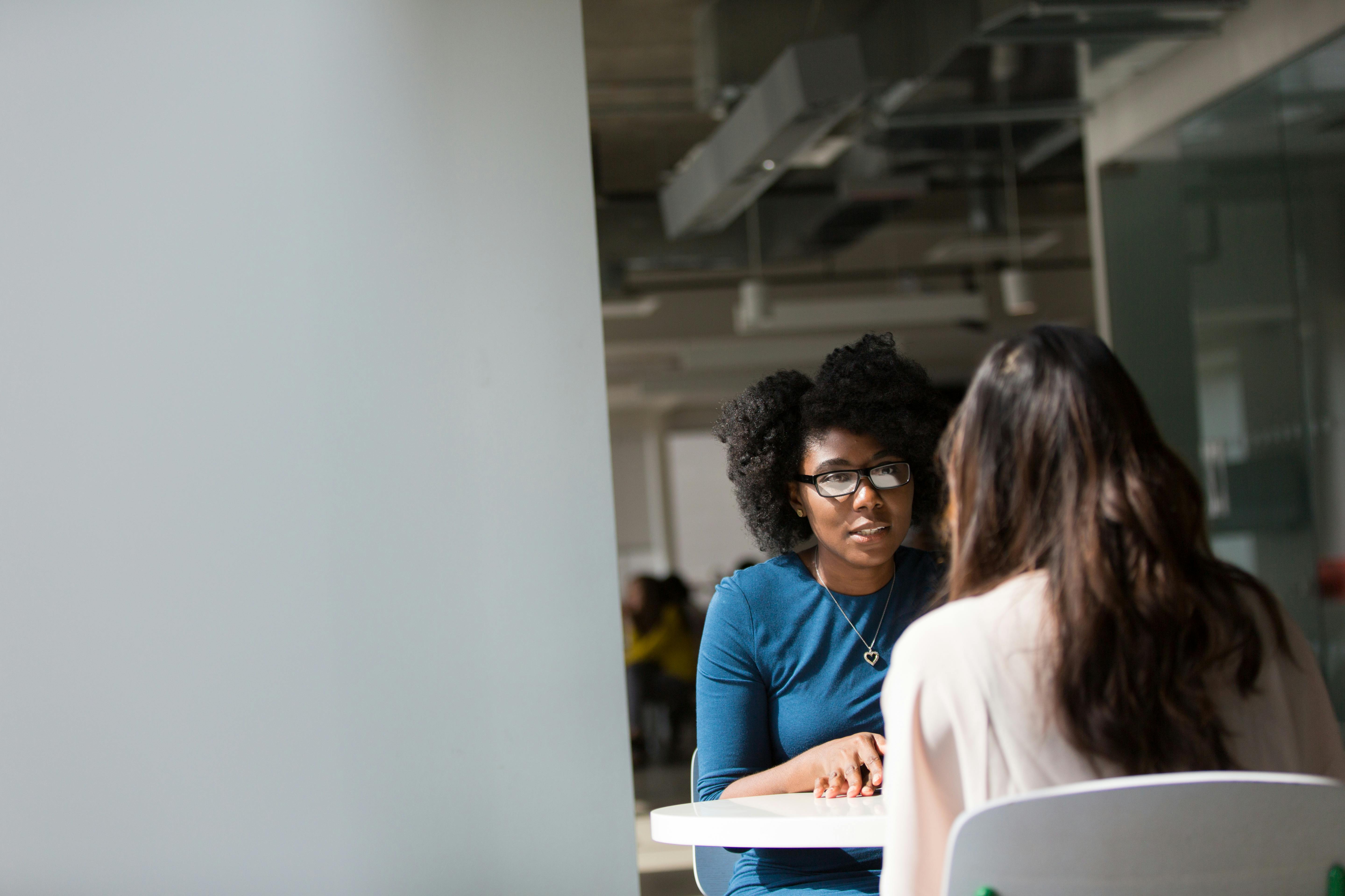Two adult women sitting across from each other at a table